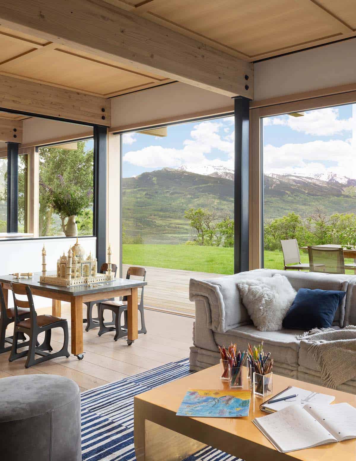 Kids' playroom with striped rug, model building, and expansive mountain-view windows