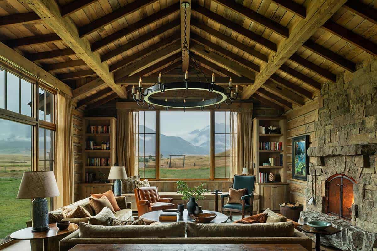 Vaulted living room with exposed beams, stone fireplace, and large mountain-view window