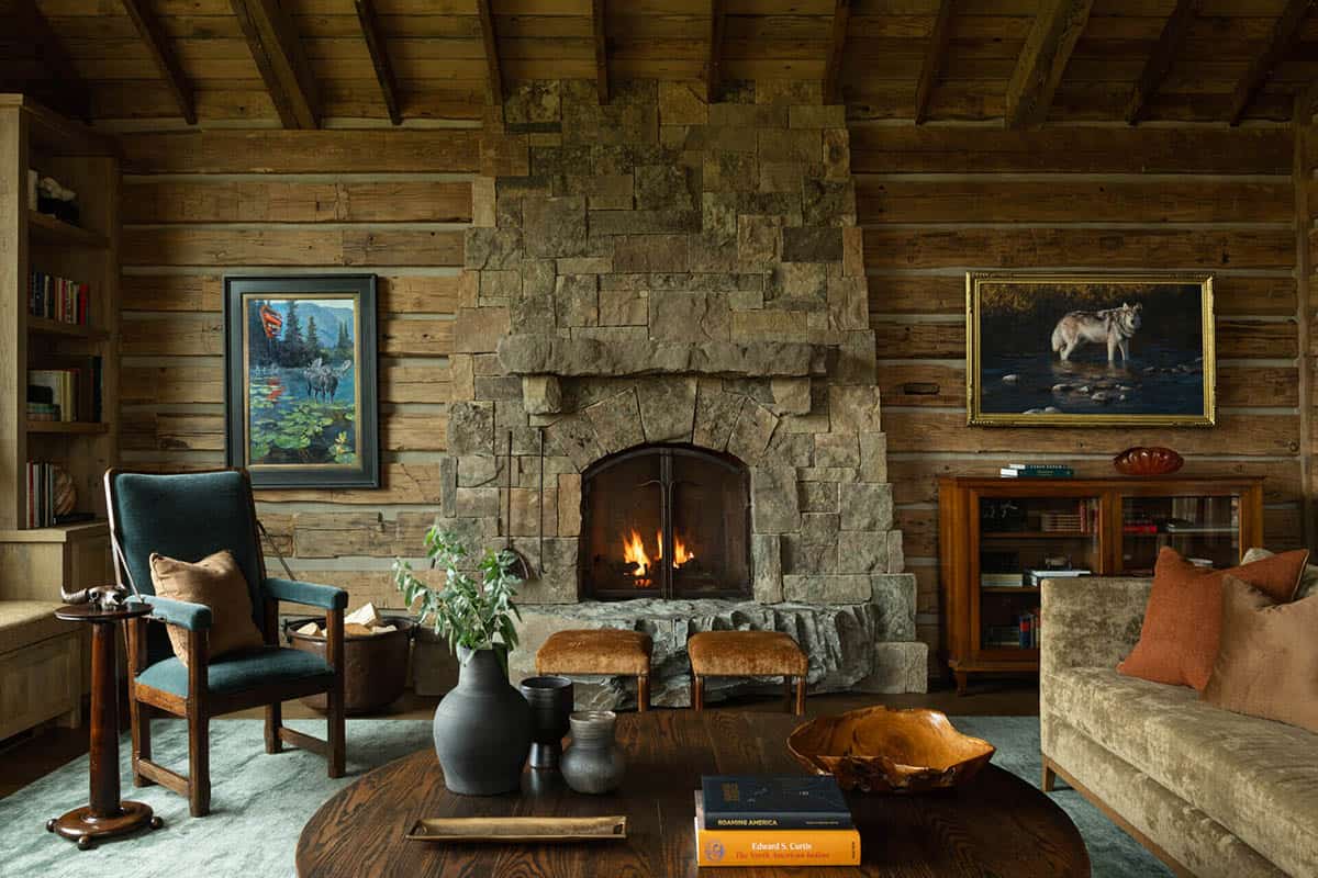 Cozy living area with stone fireplace, wildlife art, and log walls