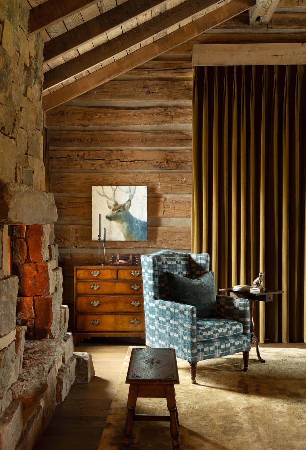 Reading nook with stone fireplace, plaid armchair, and deer painting