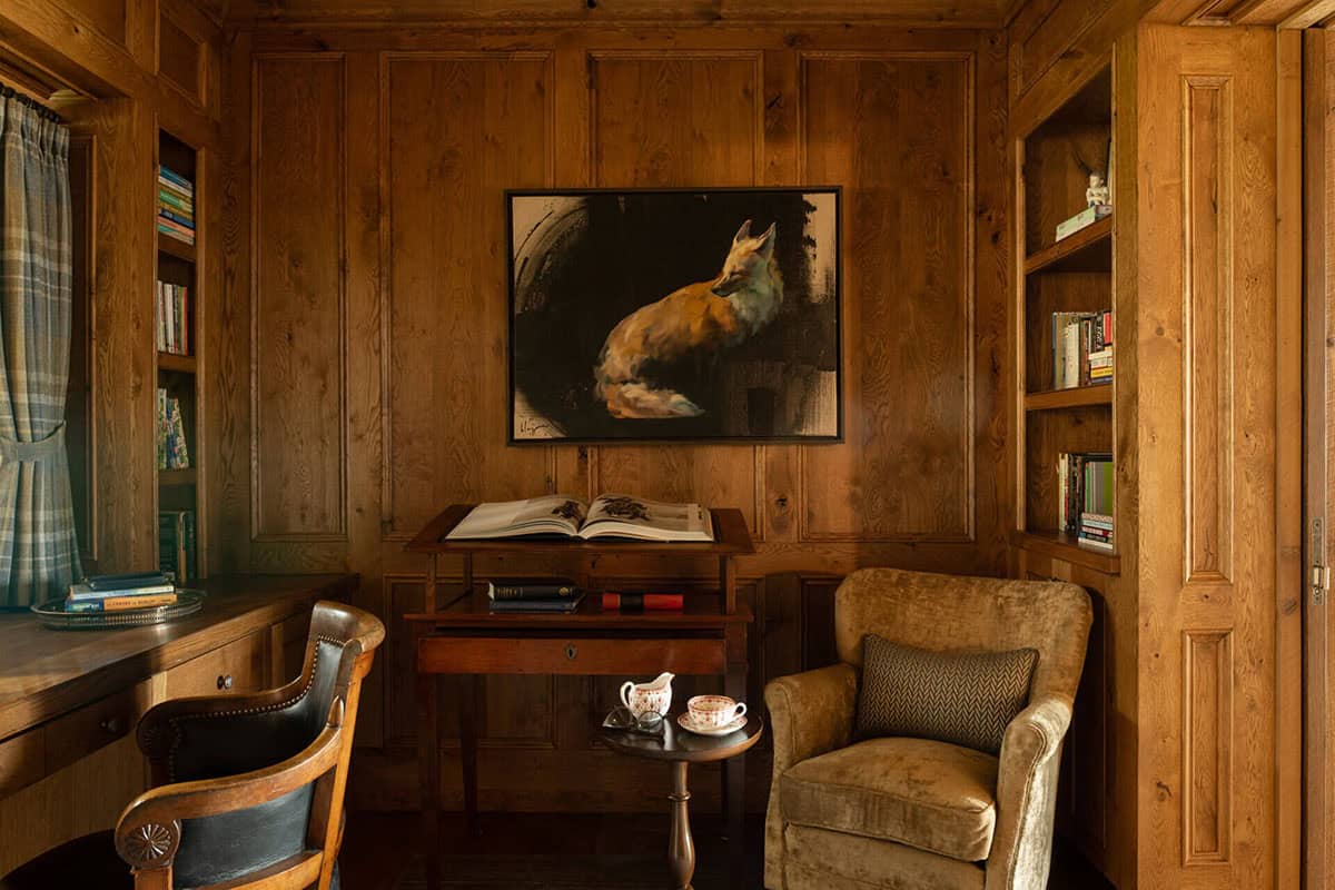 Wood-paneled study with fox painting, antique desk, and built-in bookshelves