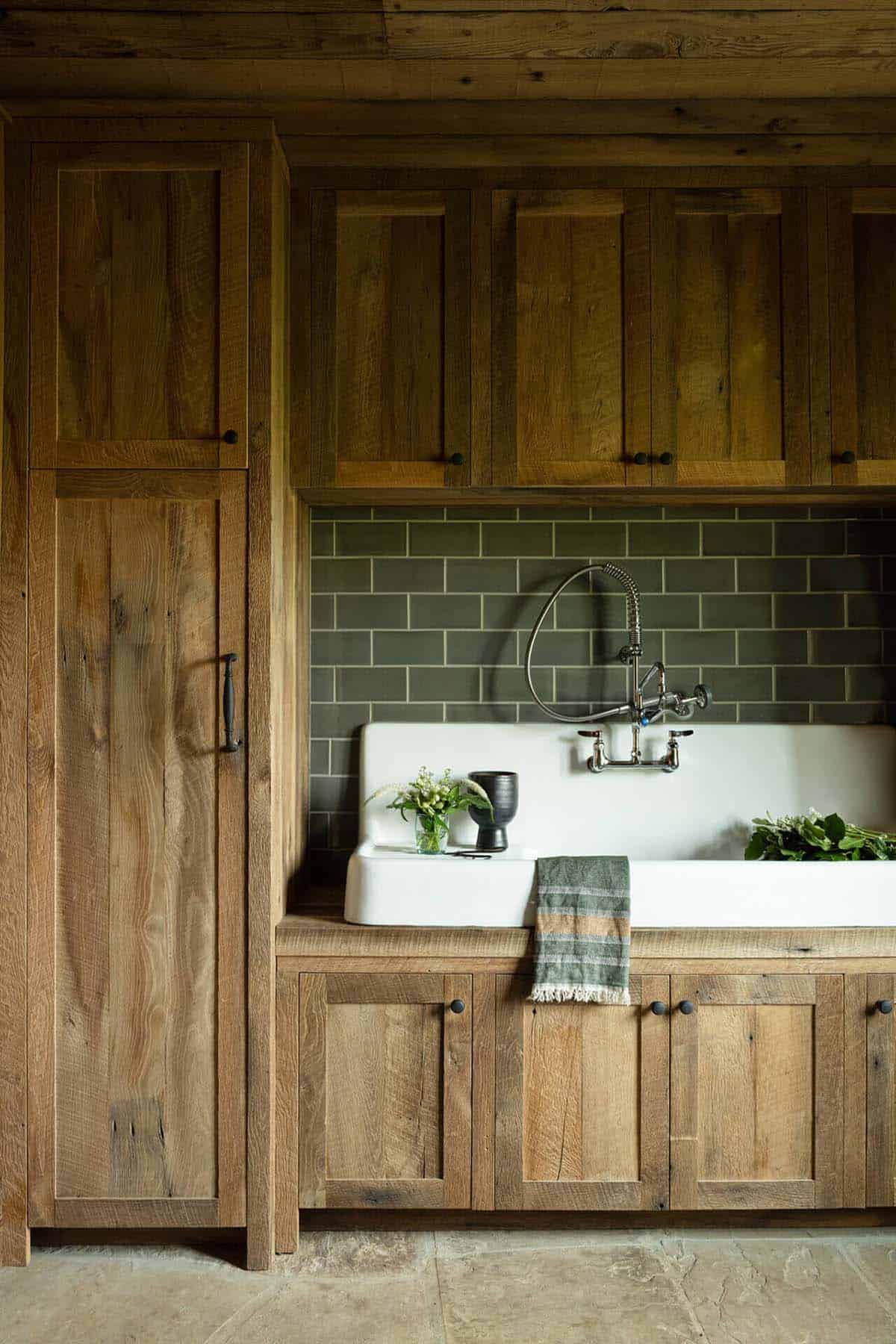 Utility sink area with green subway tile and reclaimed wood cabinetry