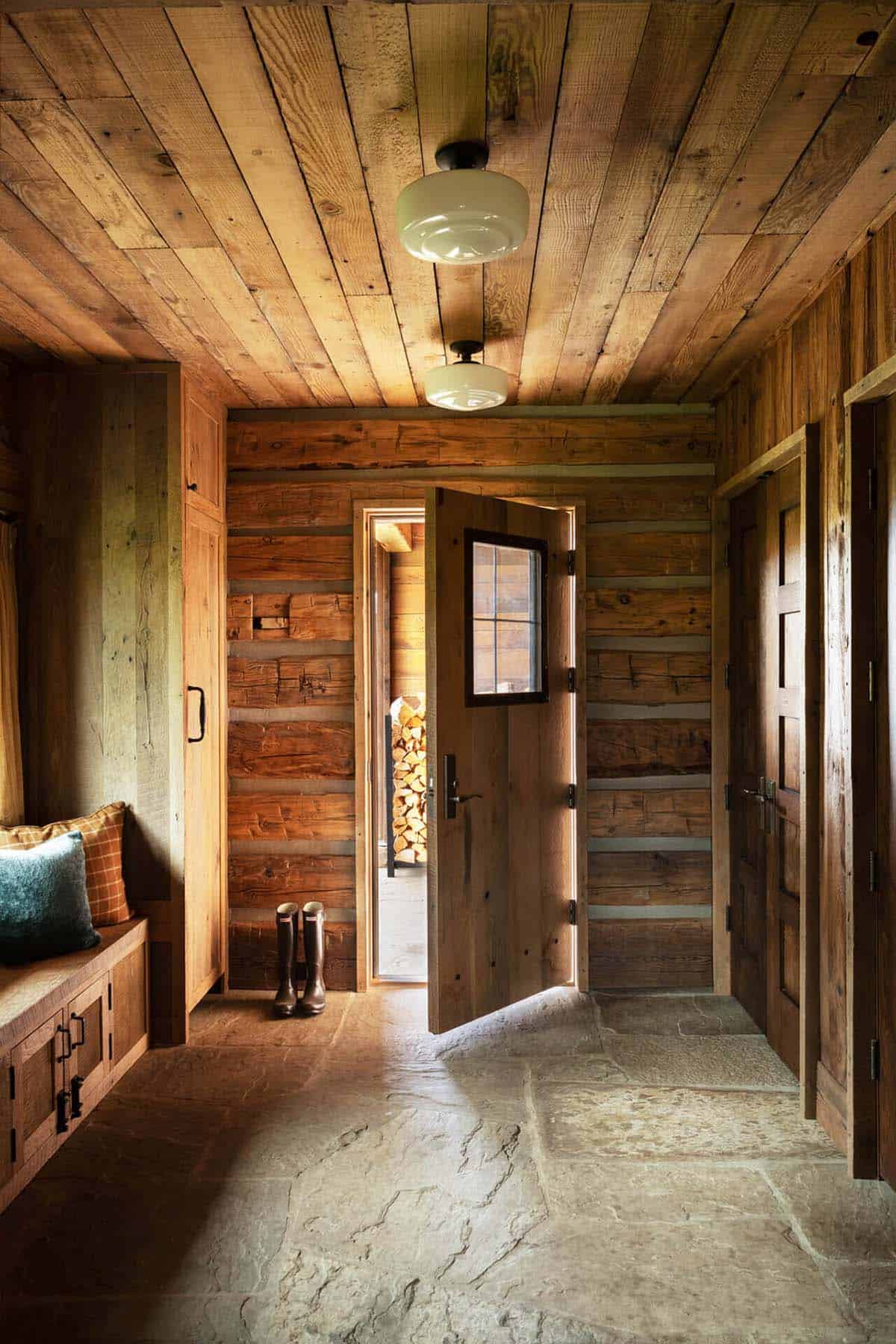 Mudroom entry with stone floor, wood paneling, and open door to woodpile