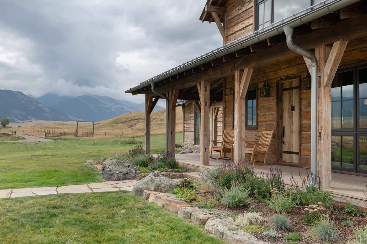 Log home porch with rocking chairs overlooking mountains and a stone pathway garden