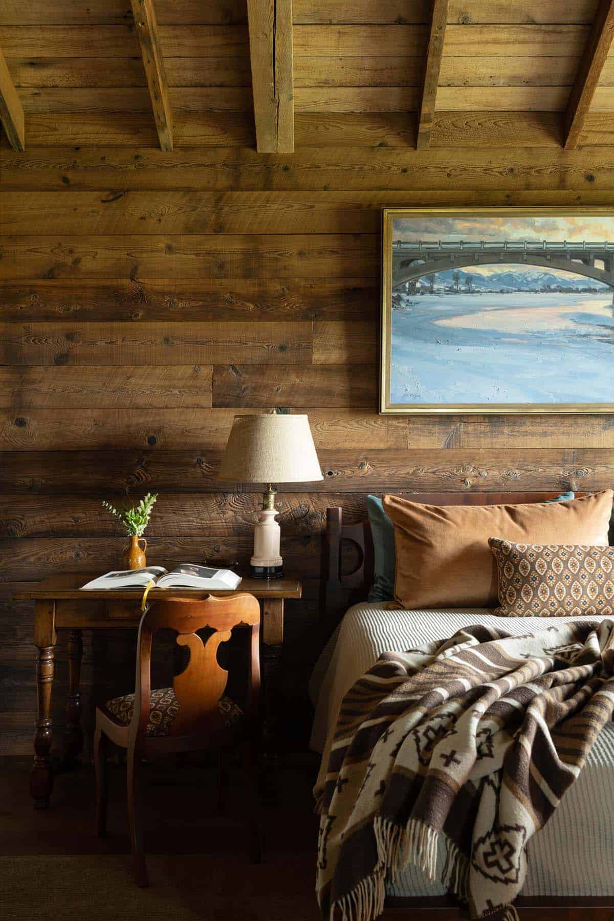 Bedroom nook with a bridge landscape painting, writing desk, and Southwestern throw blanket
