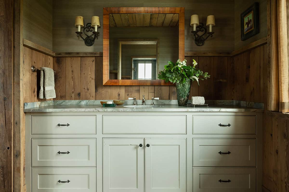 Bathroom vanity with white cabinetry, wood-framed mirror, and marble countertop