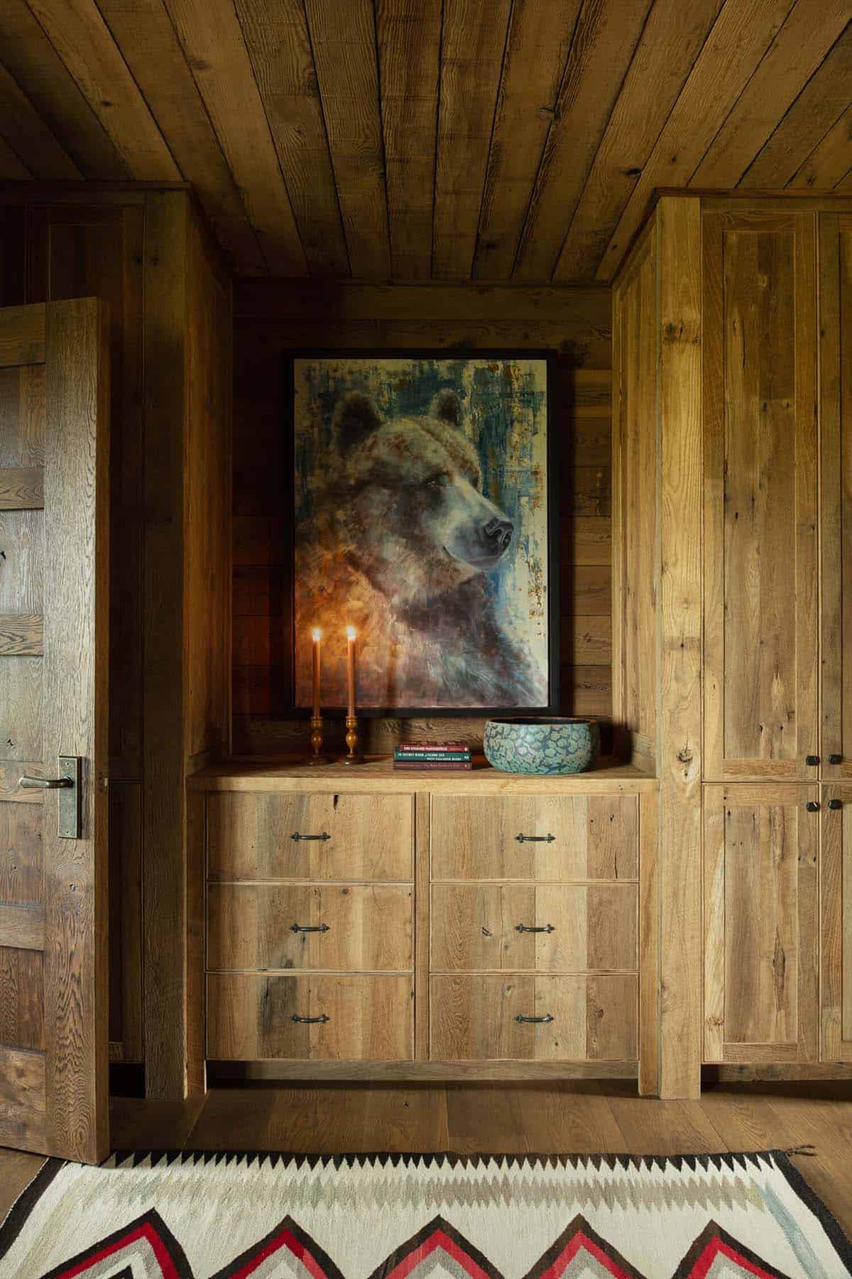 Built-in wood dresser with a bear painting, lit candles, and a Southwestern-patterned rug