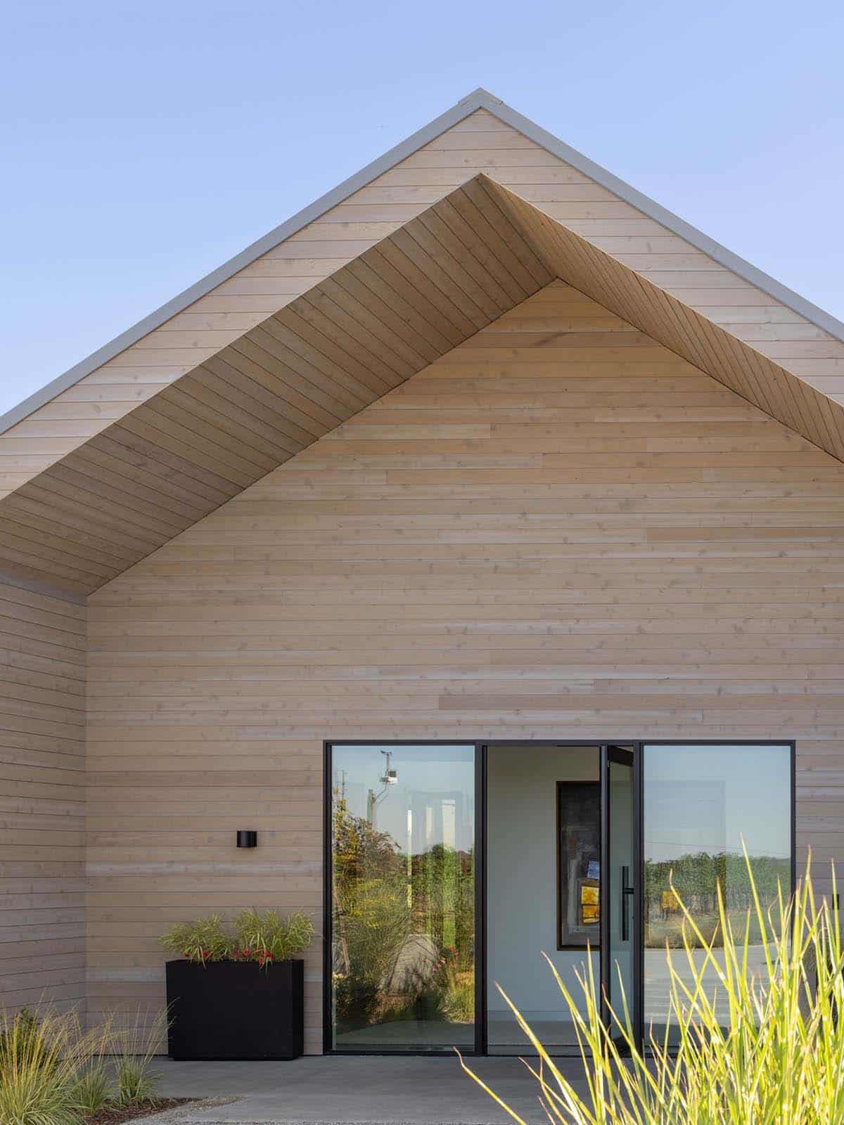 Close-up of wood-clad gable entrance with black-framed glass doors