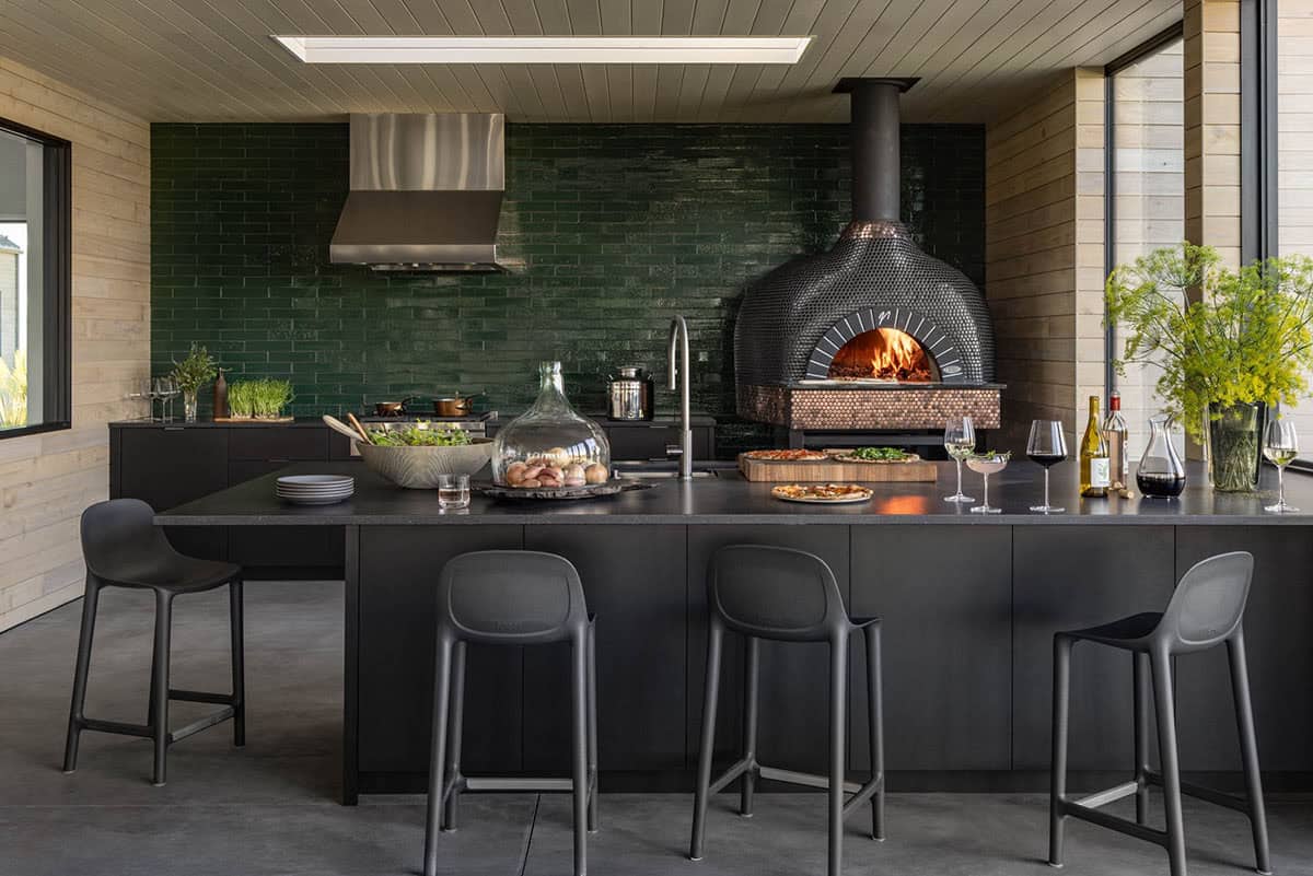Outdoor kitchen with green tile backsplash and wood-fired pizza oven