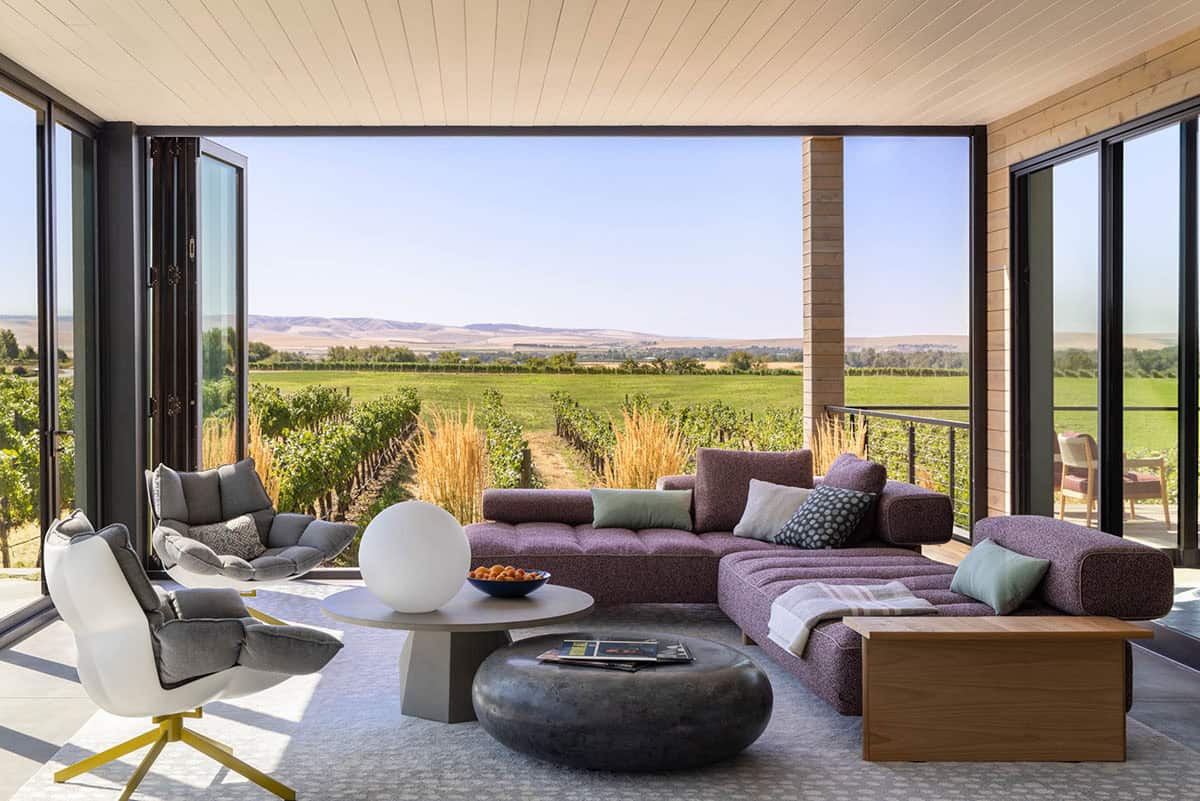 Covered patio lounge with purple sectional overlooking vineyard hills