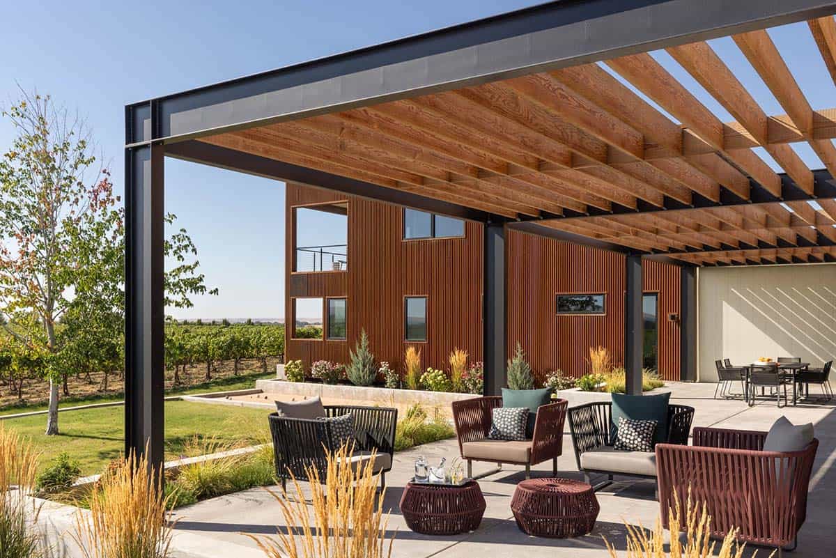 Steel-framed pergola patio with rusted metal building beyond