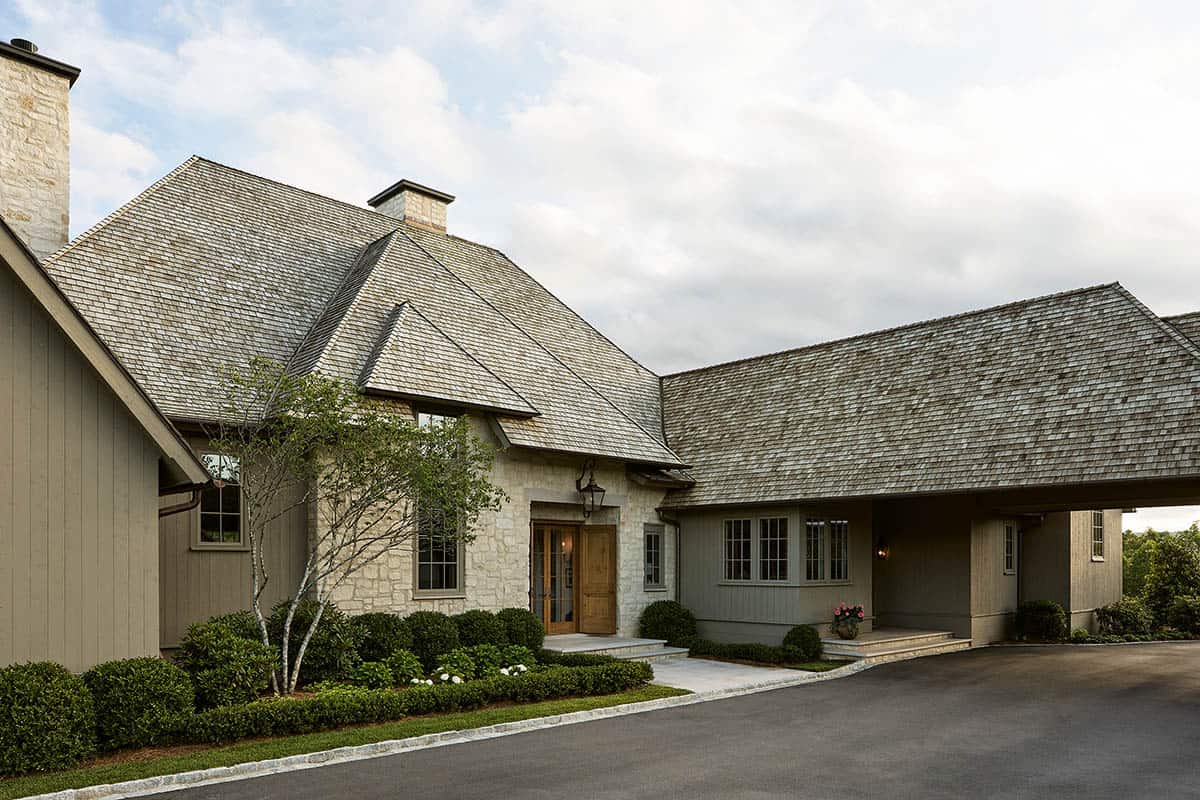Stone and shingle farmhouse exterior with cedar shake roof and carport