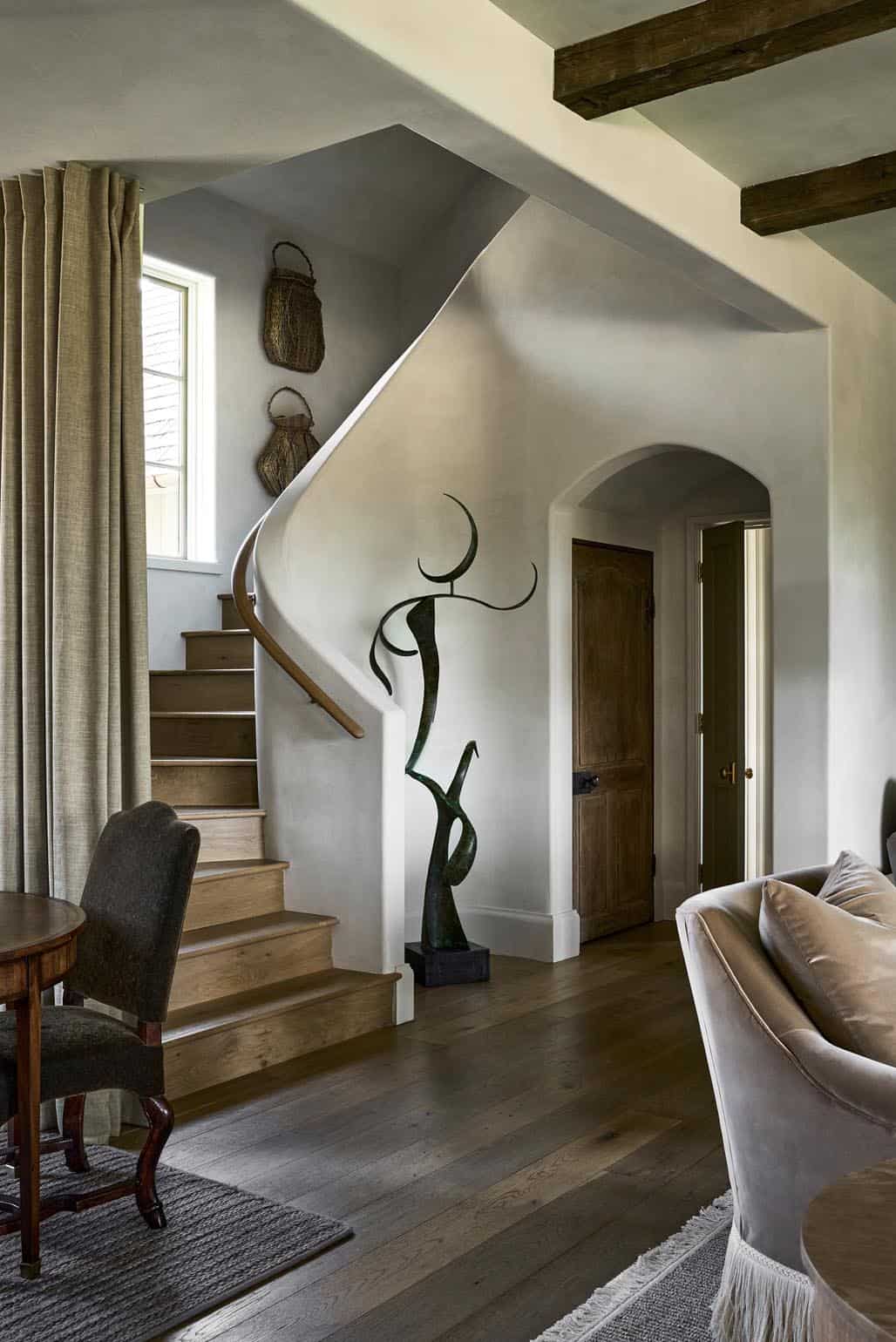 Curved staircase with wrought iron sculpture and woven basket wall decor