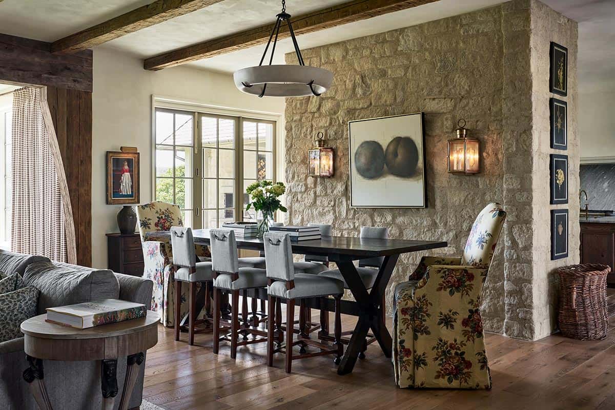 Stone dining nook with reclaimed table, floral chairs and iron sconces