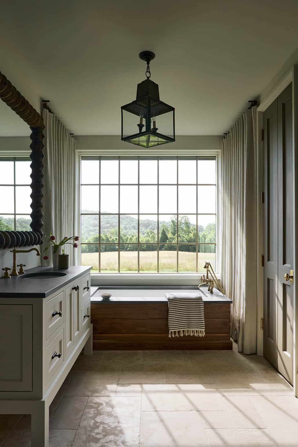 Freestanding wood tub beneath grid windows overlooking open pasture