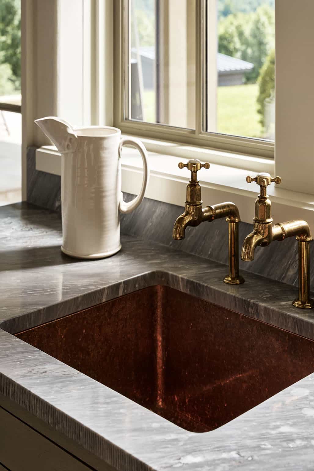 Copper farmhouse sink with vintage brass bib taps and ceramic pitcher