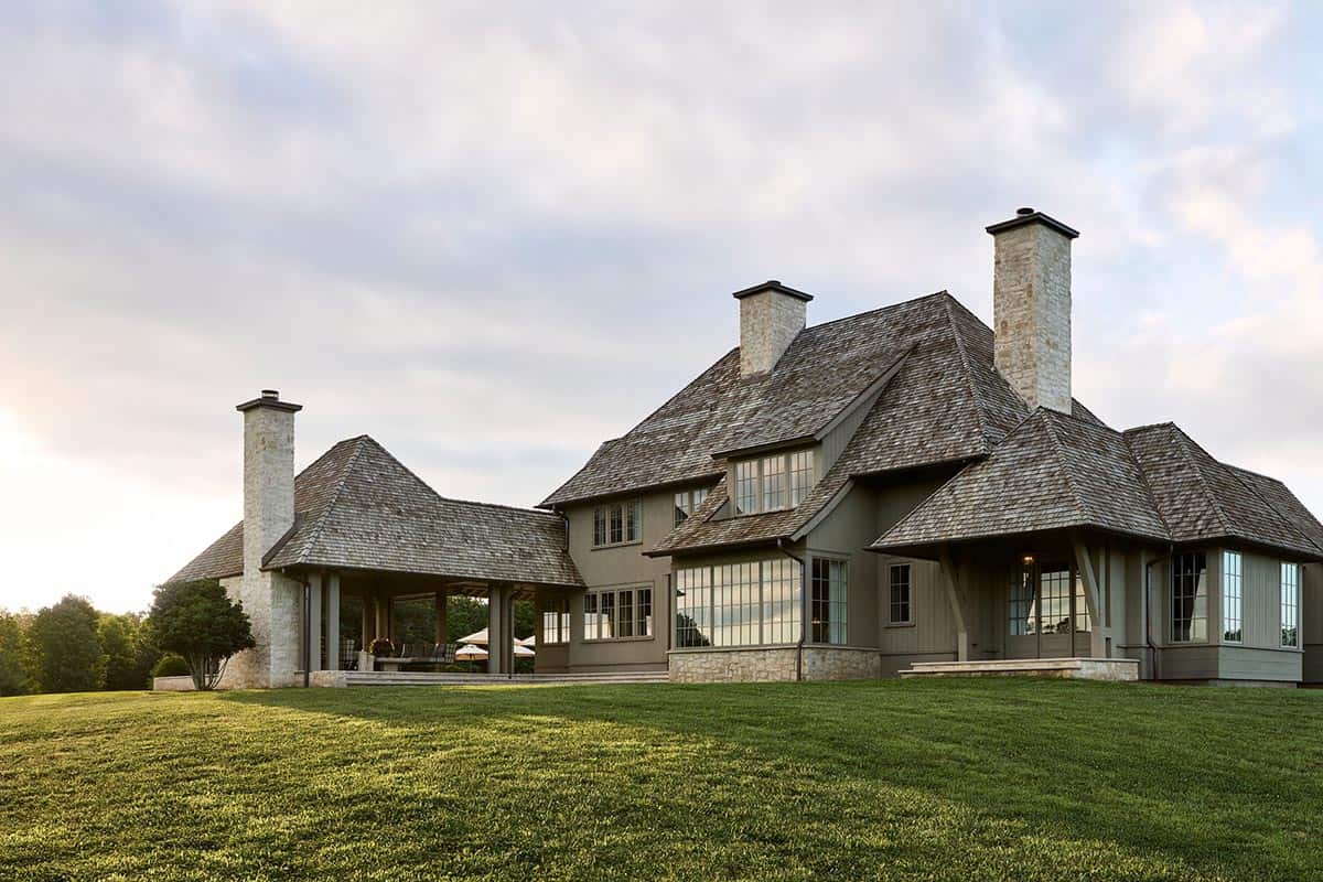 Rear exterior view of shingled farmhouse with multiple stone chimneys