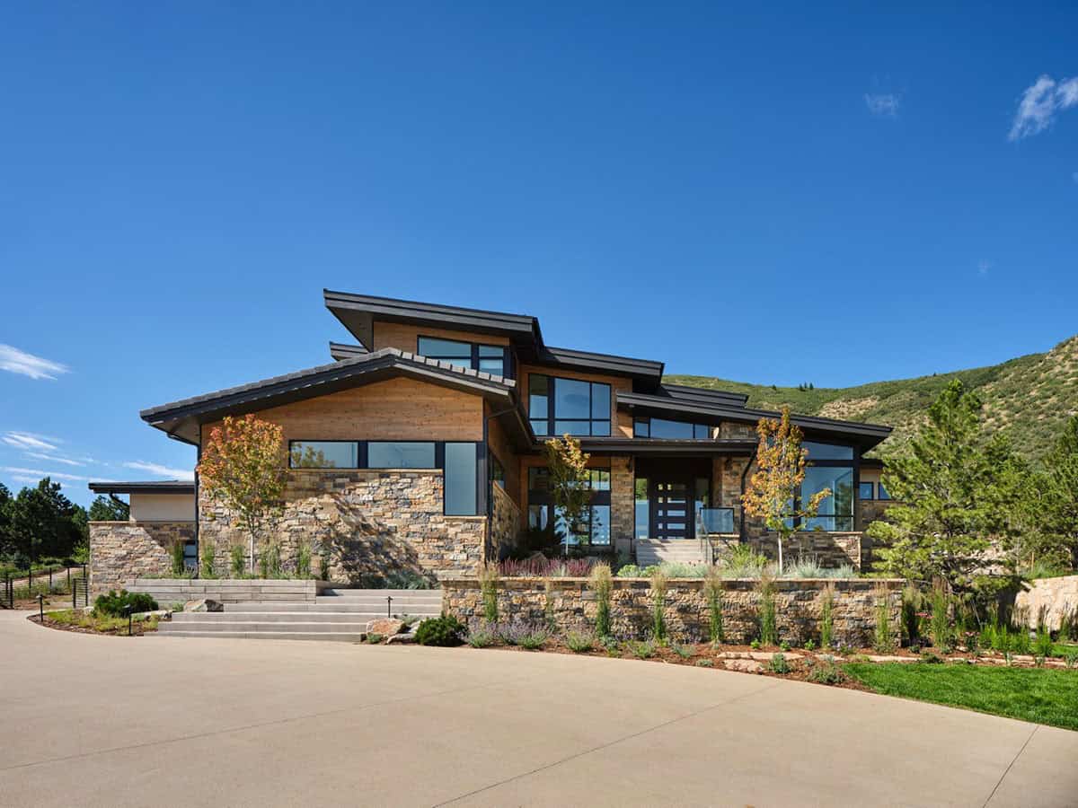 Front view of mountain modern house with layered shed roofs, stone base, and wood siding