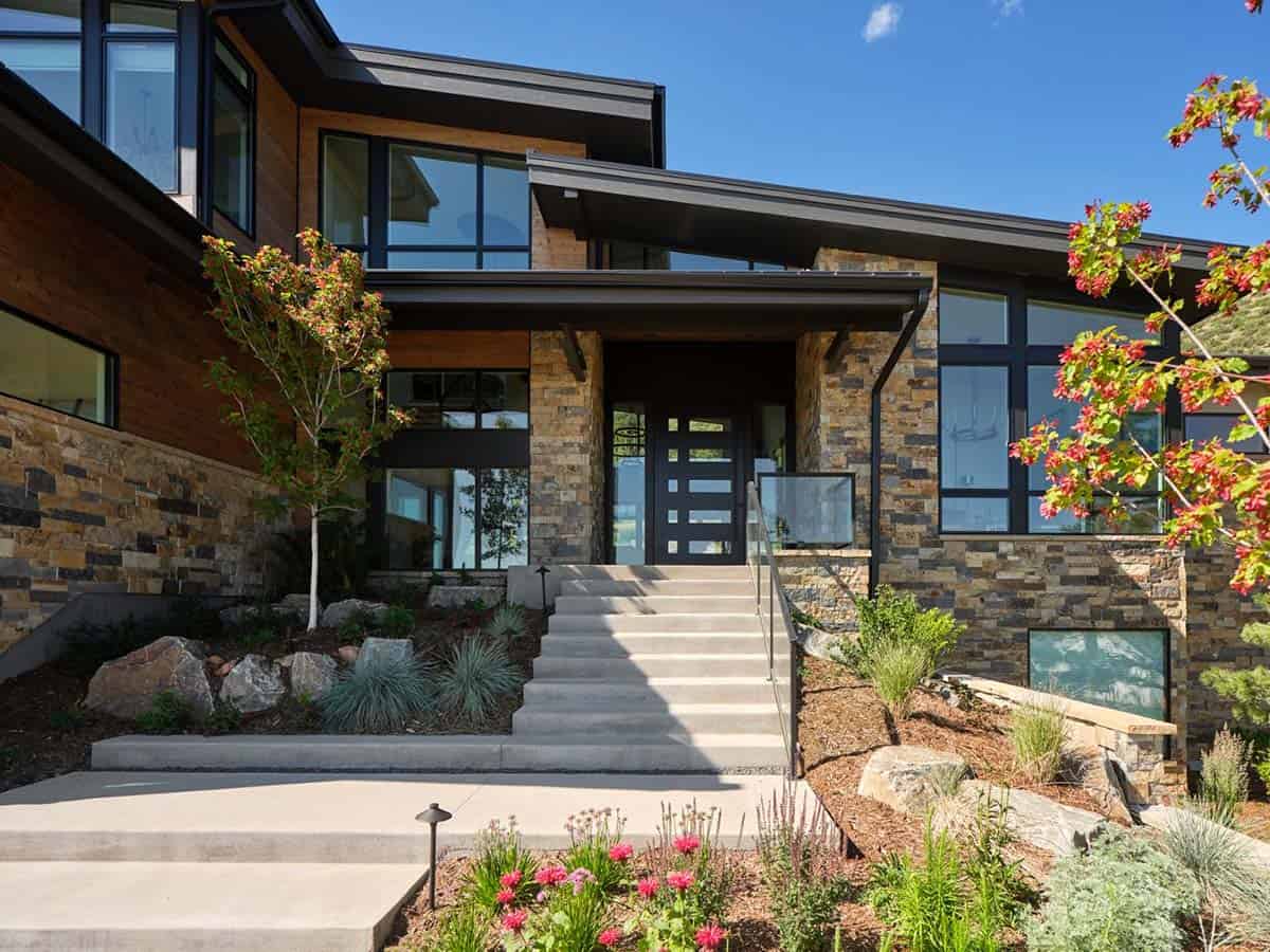 Front entrance with black door, stone steps, and flowering tree