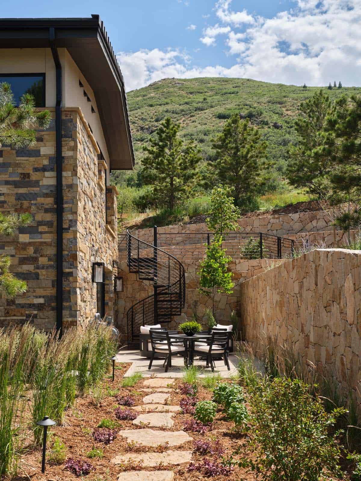 Side courtyard with stone walls, spiral staircase, and outdoor dining table