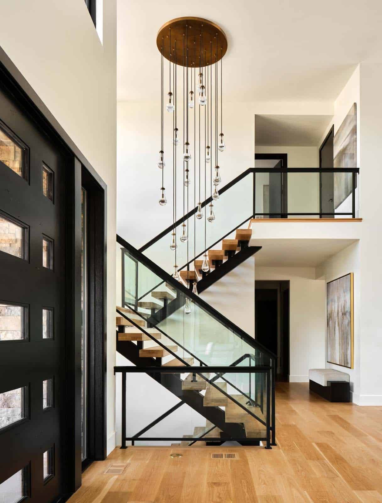 Entryway with floating wood staircase, glass railing, and long teardrop chandelier