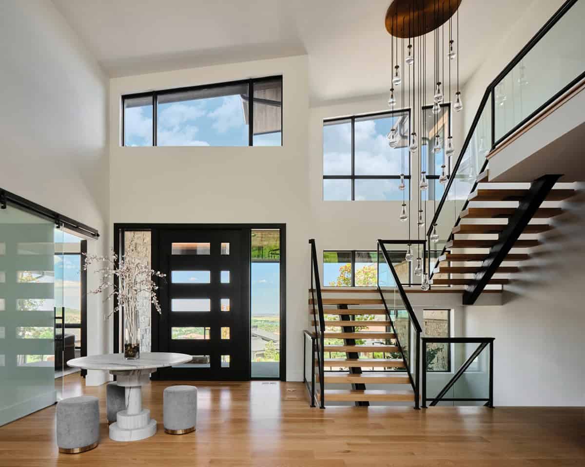 Foyer with round marble table, black front door, and open staircase