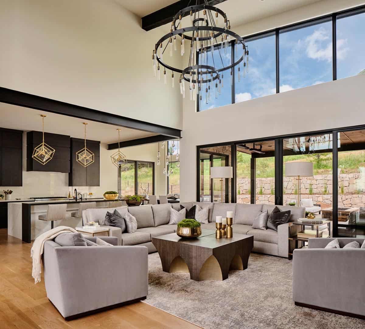 Open-concept living and kitchen area with tall windows and layered ring chandelier