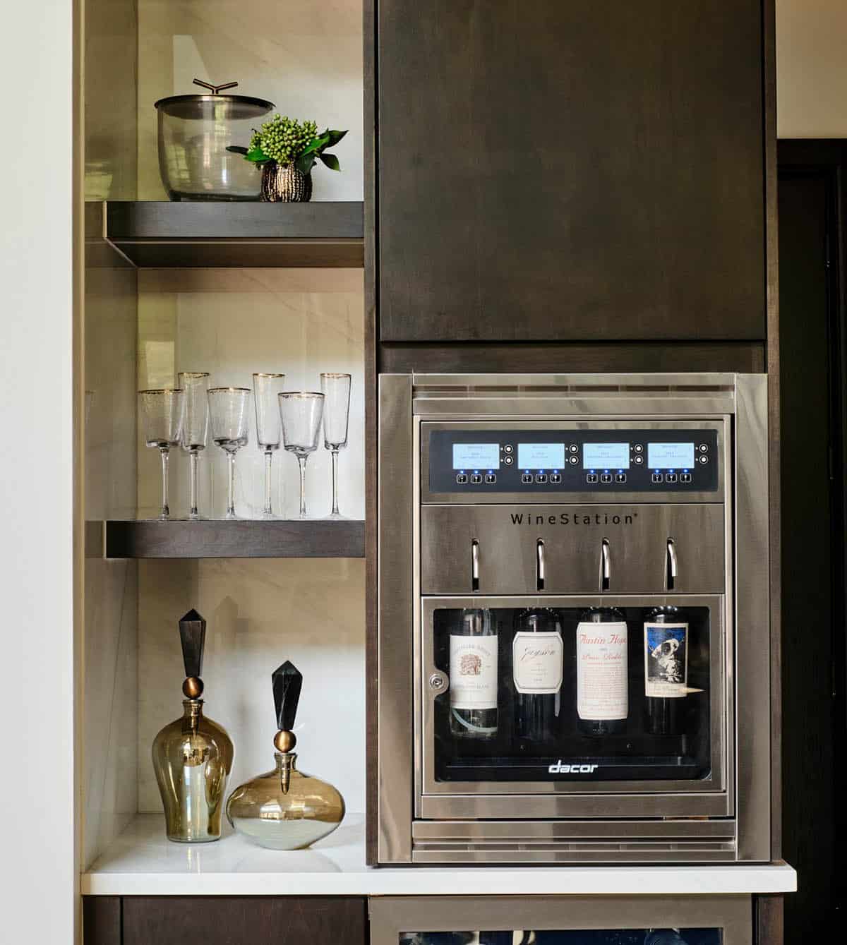 Built-in wine dispensing station with glassware and decanters on open shelves
