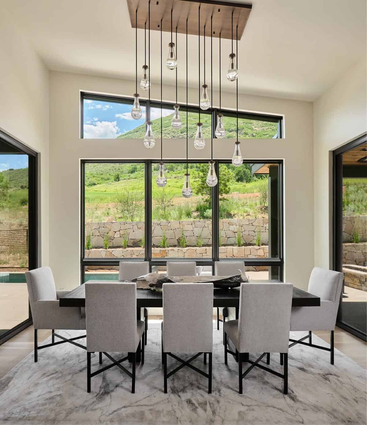 Dining room with dark wood table, gray upholstered chairs, and teardrop pendant chandelier