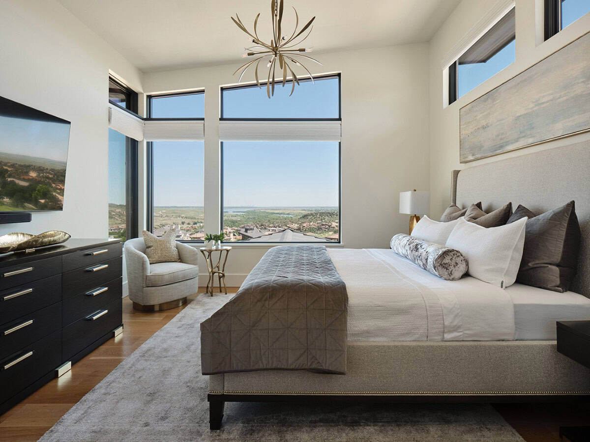 Primary bedroom with upholstered bed, city and lake views through corner windows