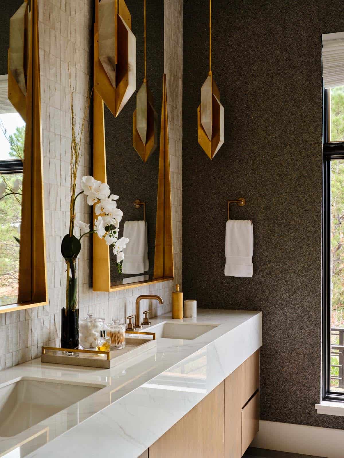 Close-up of gold faceted pendant sconces and marble double vanity in bathroom