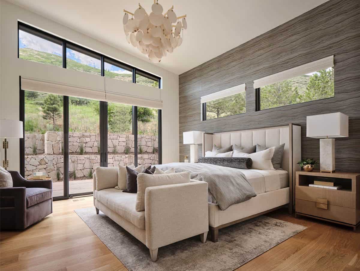 Bedroom with wave-patterned wallpaper accent wall, upholstered bed, and shell-style chandelier