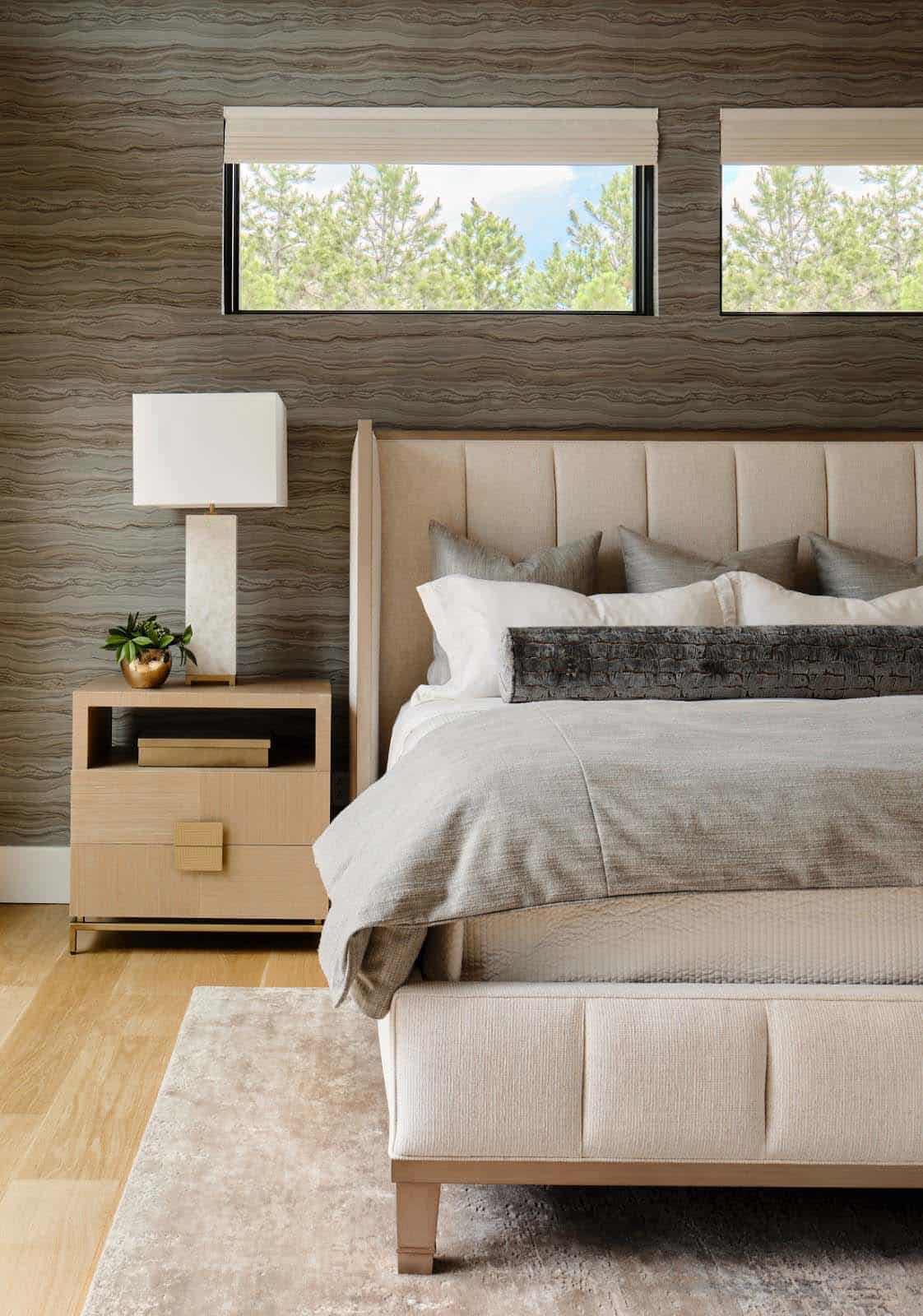 Bedside view of tufted headboard, wood nightstand, and marble table lamp