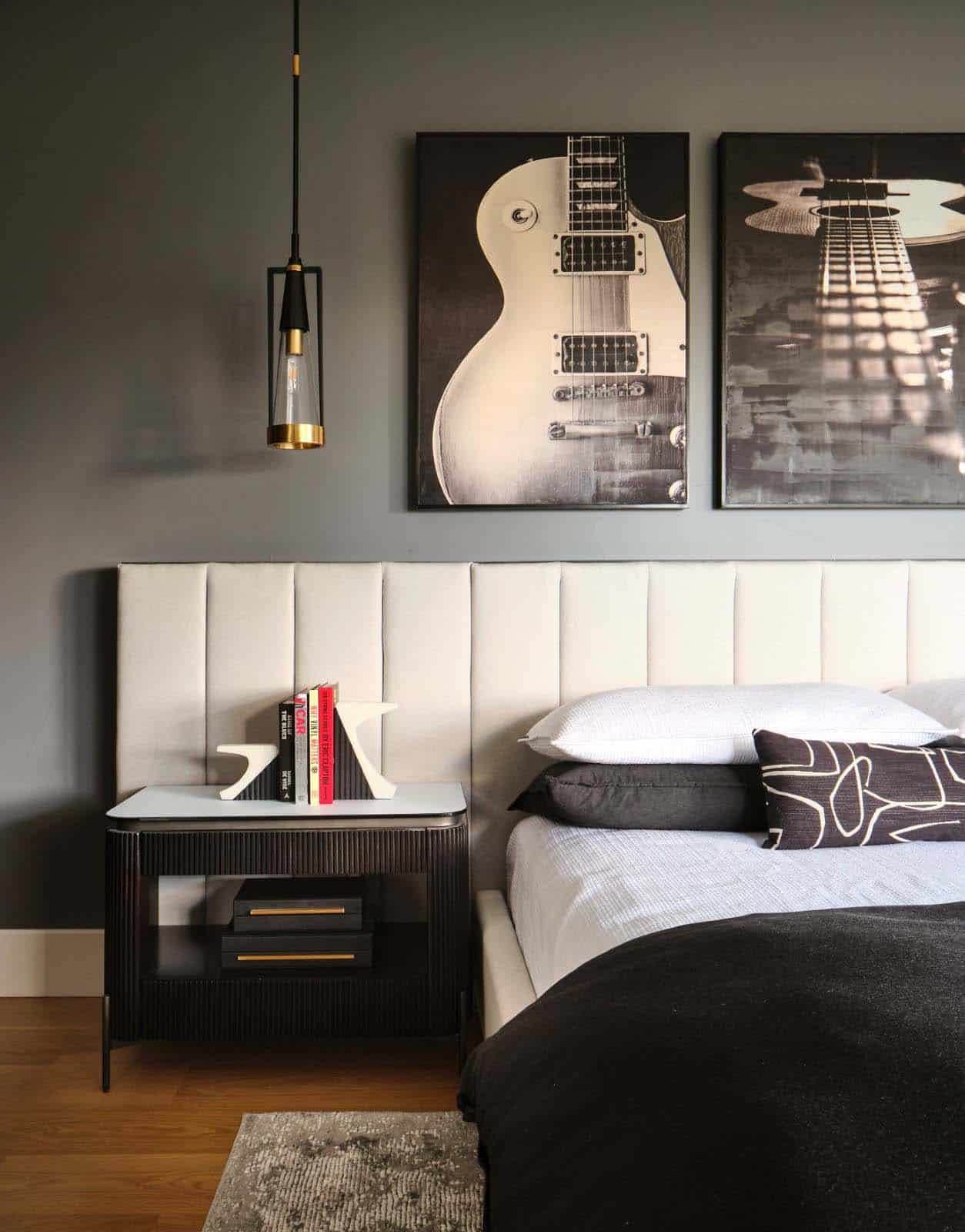 Bedside detail with ribbed black nightstand, guitar artwork, and pendant light