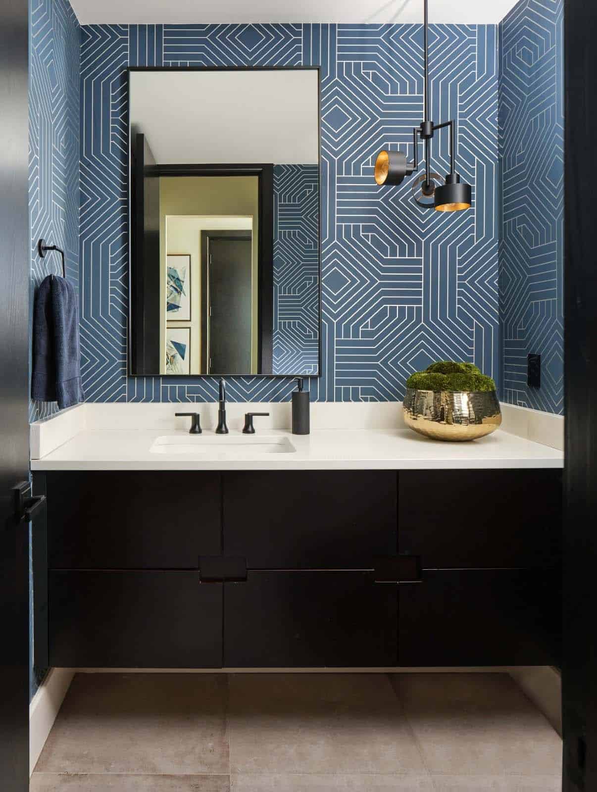 Powder room with bold blue geometric wallpaper and black modern sconce fixture