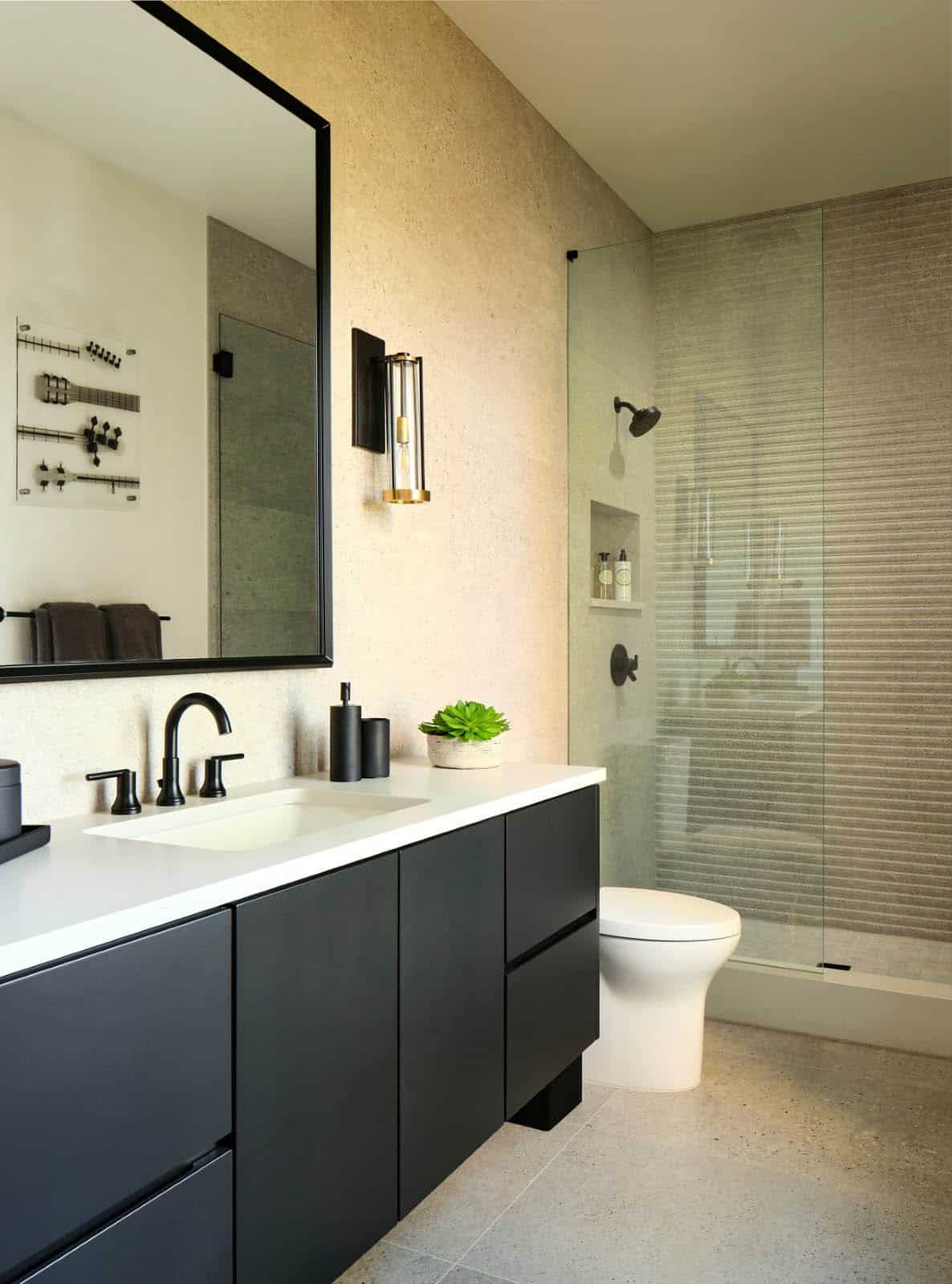 Bathroom with black vanity, glass shower enclosure, and ribbed tile accent wall