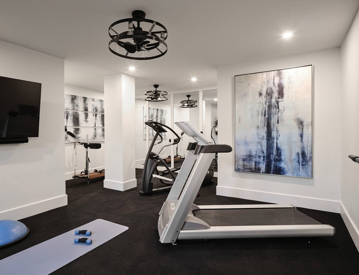 Home gym with treadmill, elliptical, mirrored wall, and abstract black-and-white artwork