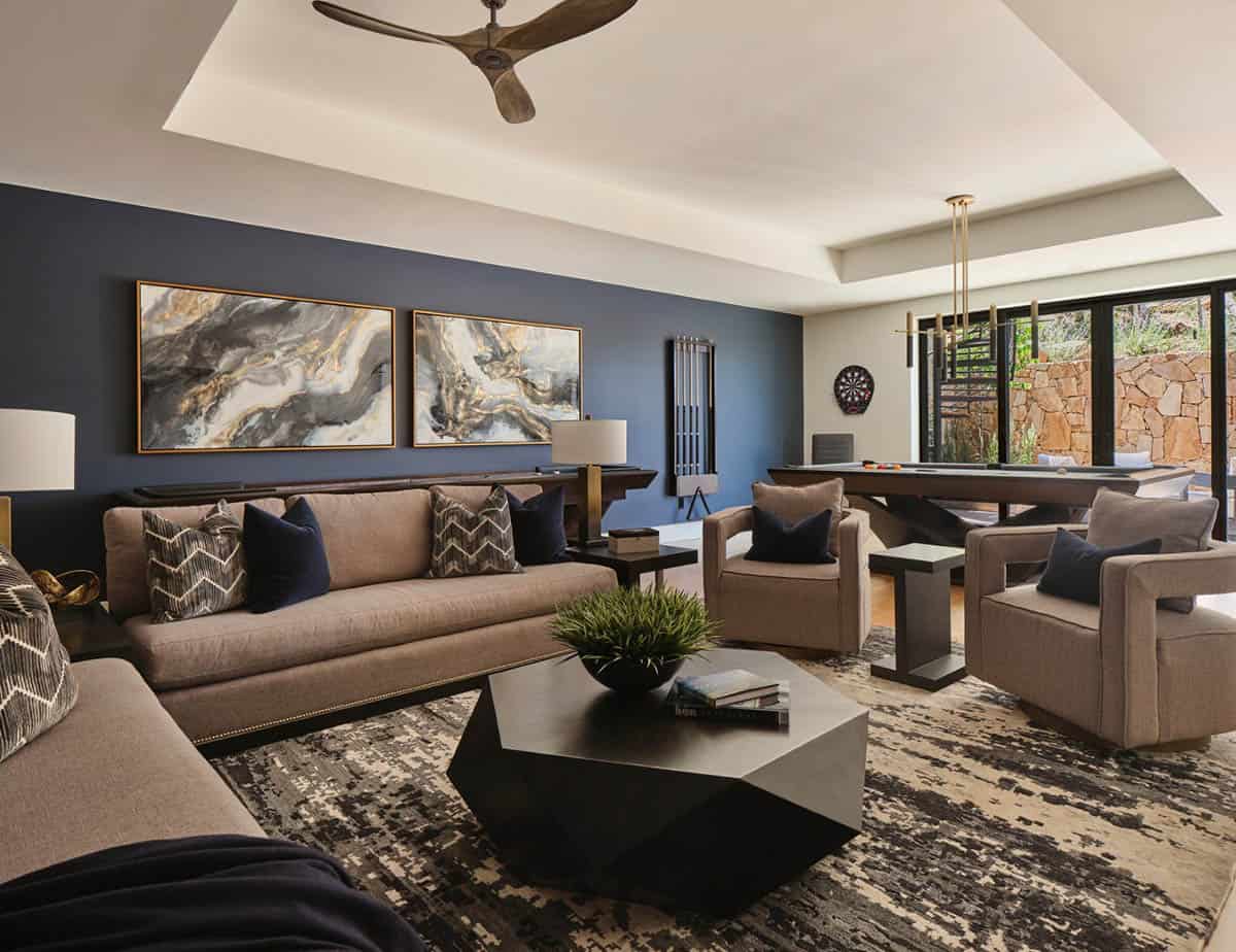 Game room with billiards table, taupe sofas, blue accent wall, and marble-style artwork