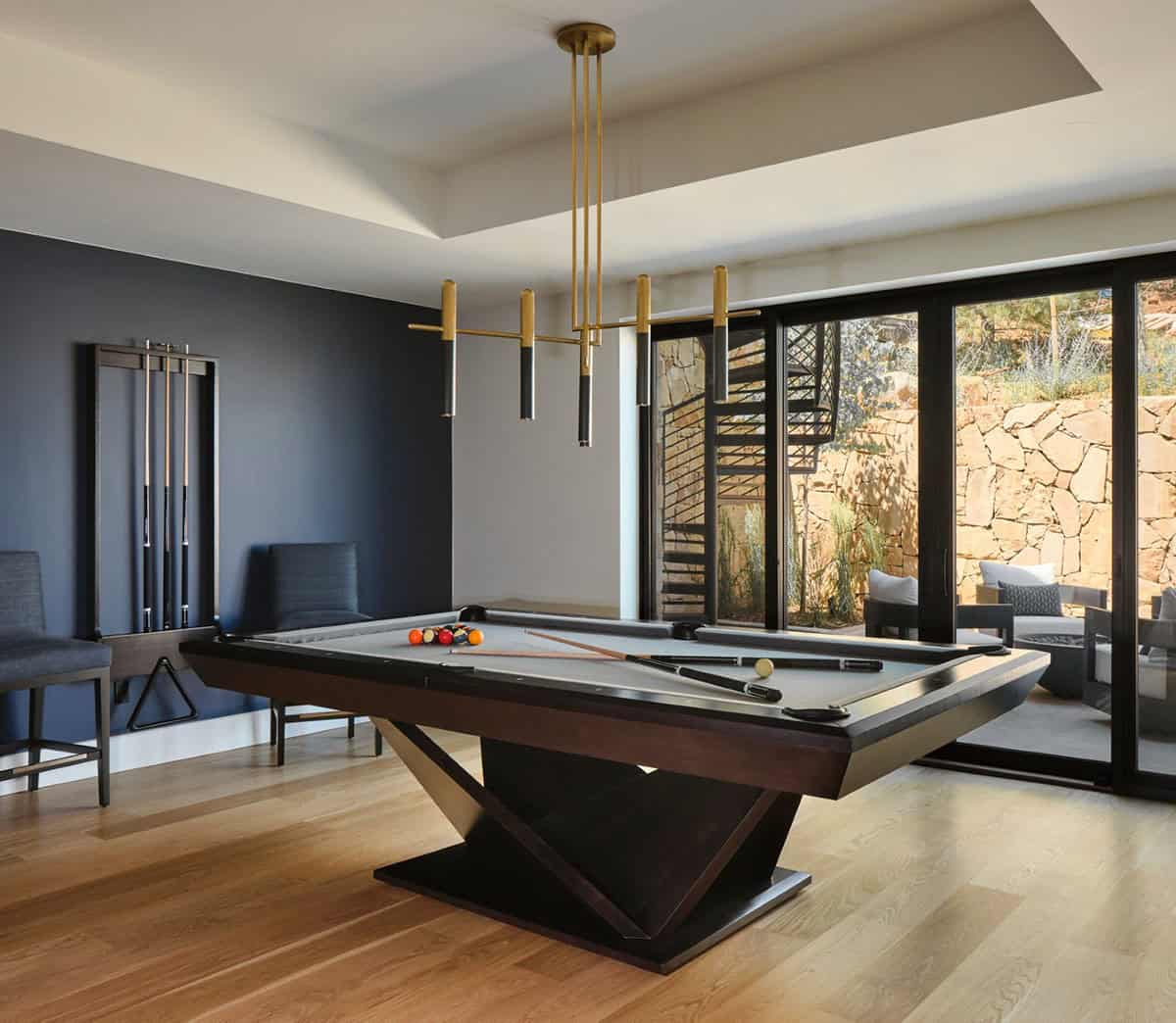 Billiards room with pool table, cue rack, brass tube chandelier, and patio views
