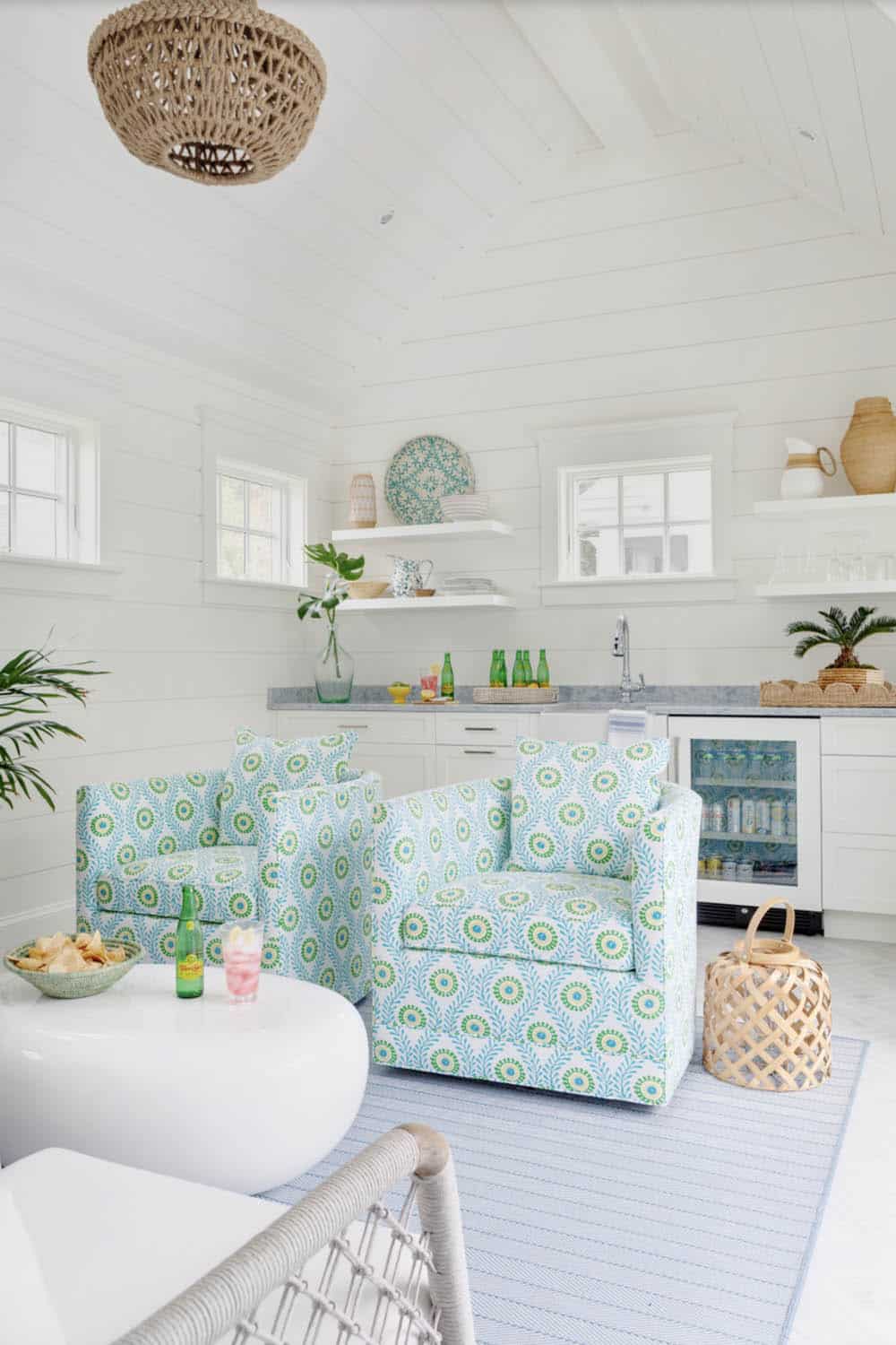 Pool house sitting area with blue floral swivel chairs and wet bar