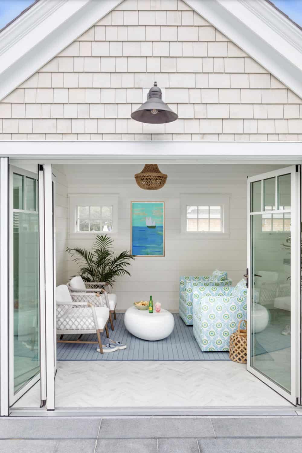 Exterior view of shingled pool house with folding glass doors open