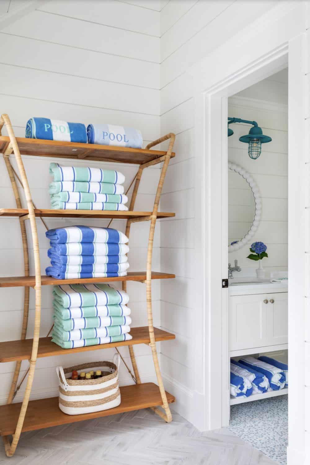 Rattan shelving stocked with folded pool towels near bathroom entrance