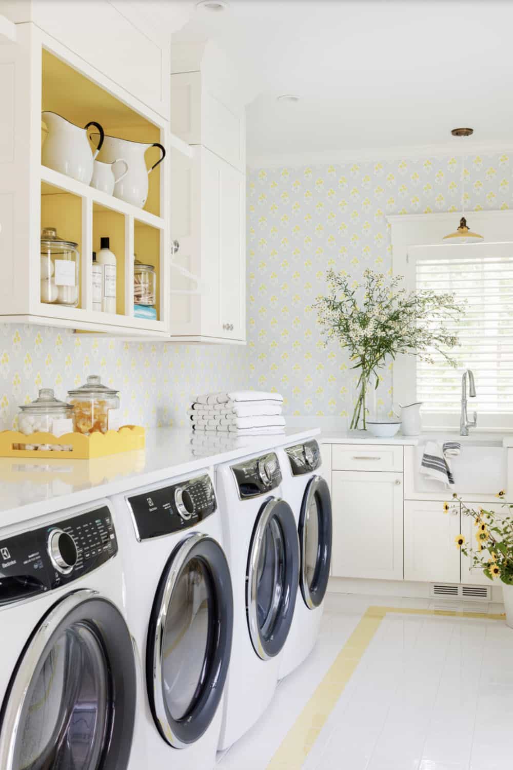 White laundry room with four appliances and floral wallpaper accents