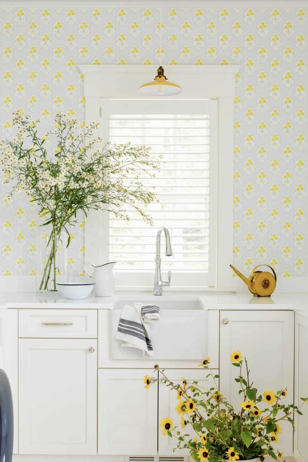 Farmhouse sink beneath window flanked by sunflowers and daisy wallpaper