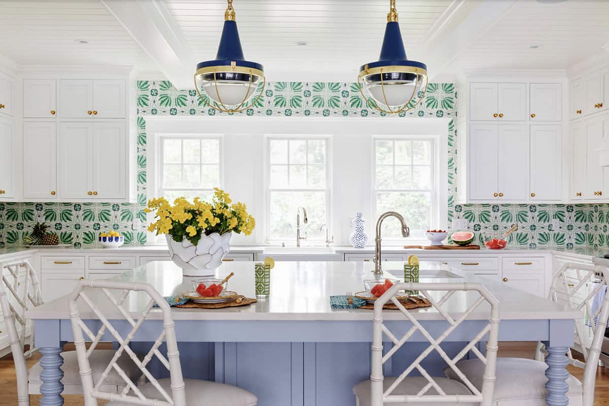 Wide kitchen view showing tiled backsplash and blue pendant lighting