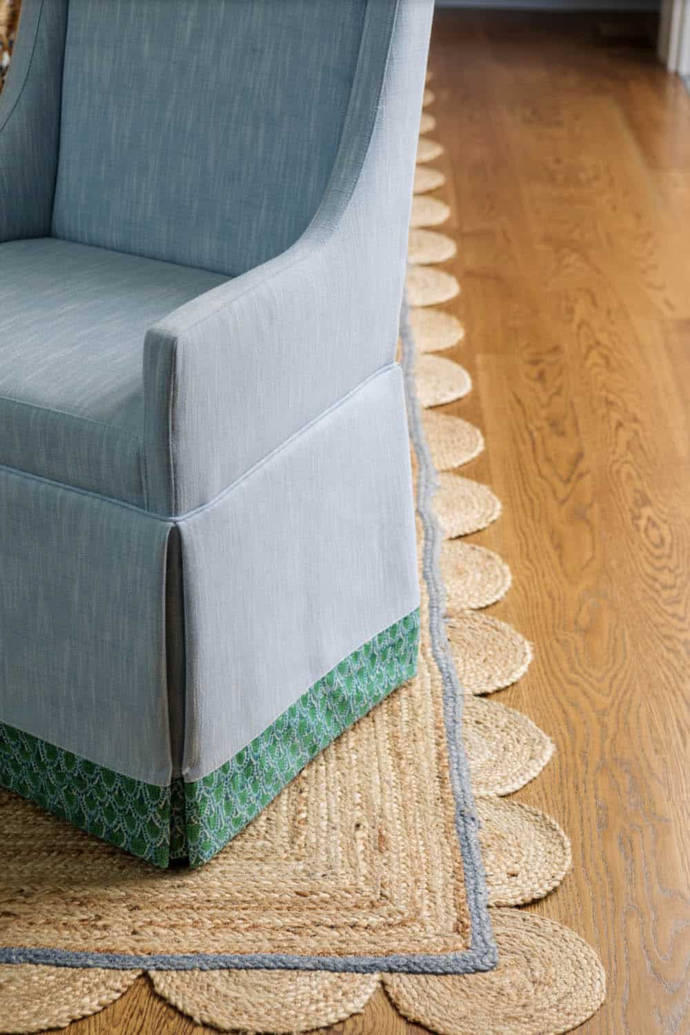 Skirted blue armchair detail atop scalloped jute area rug
