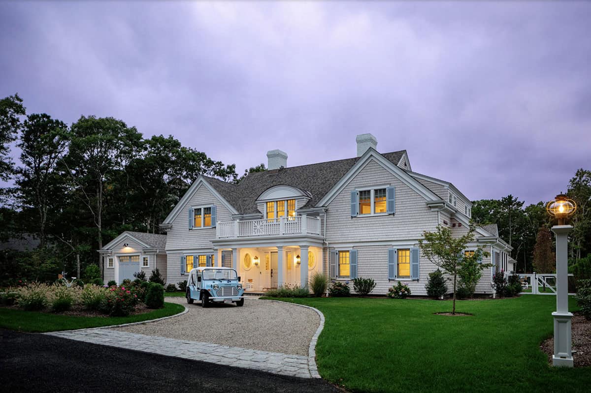 Twilight view of shingle style home with vintage blue Moke