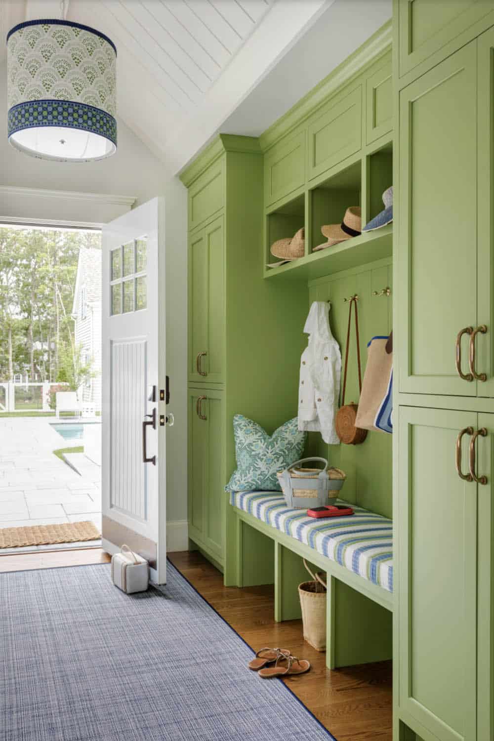 Green mudroom with striped bench and built in storage cubbies