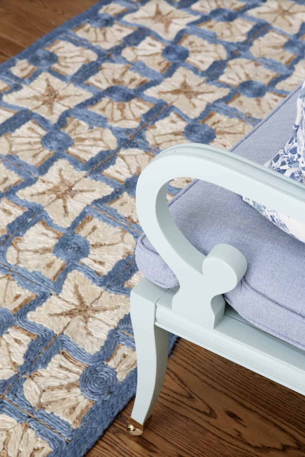 Detail of blue chair arm beside patterned area rug