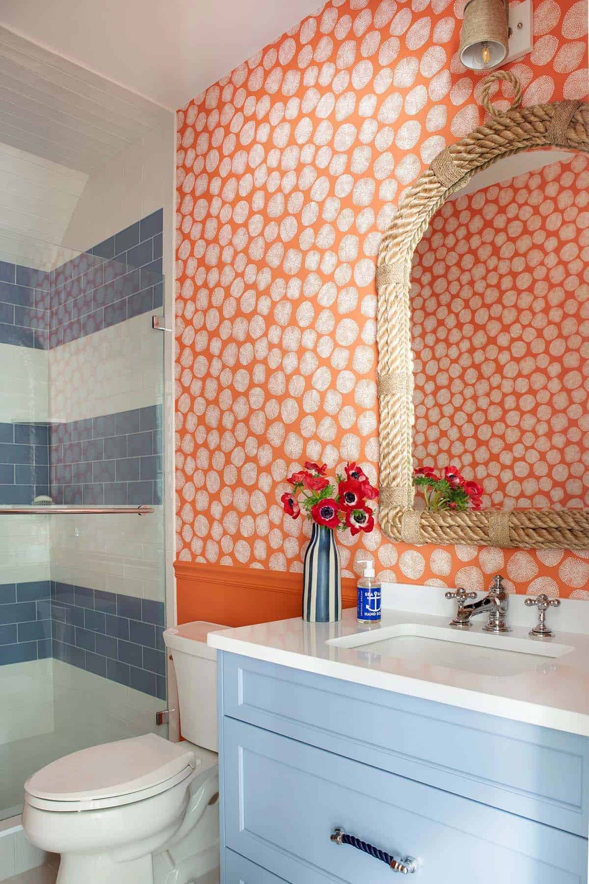 Bathroom with orange dotted wallpaper and rope framed mirror